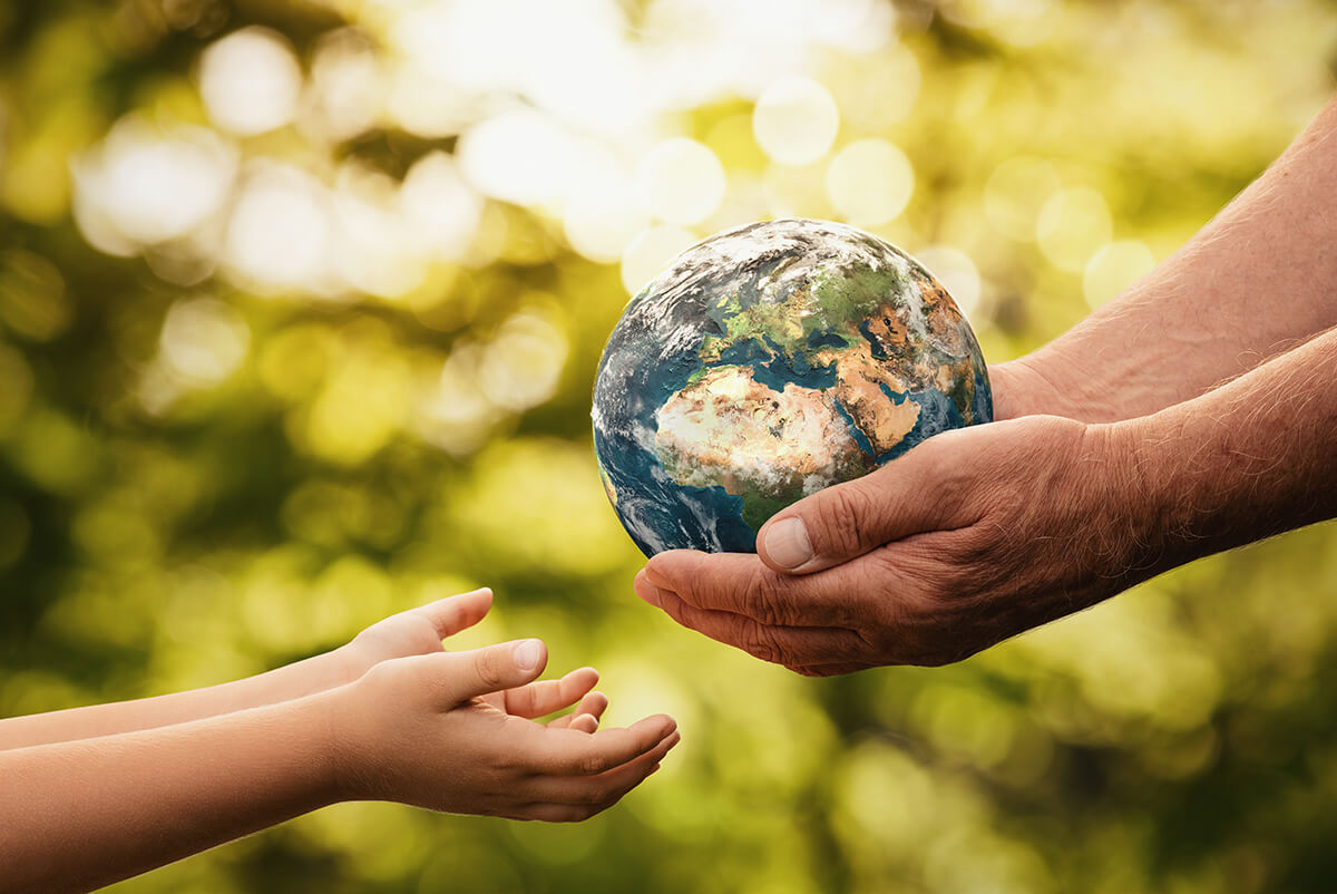senior hands giving small planet earth to a child